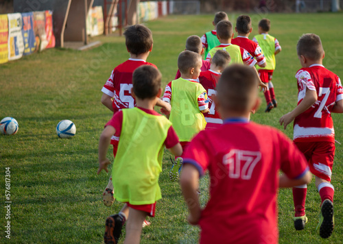Children practicing soccer run on the field