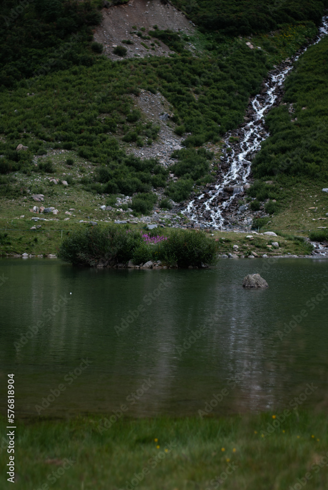 View on lake near waterfall in green mountains in Alps View on lake near waterfall in green mountains in Alps