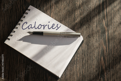 notes na stole z kartką z napisem Calories. Koncepcja diety, zapisywania posiłków.