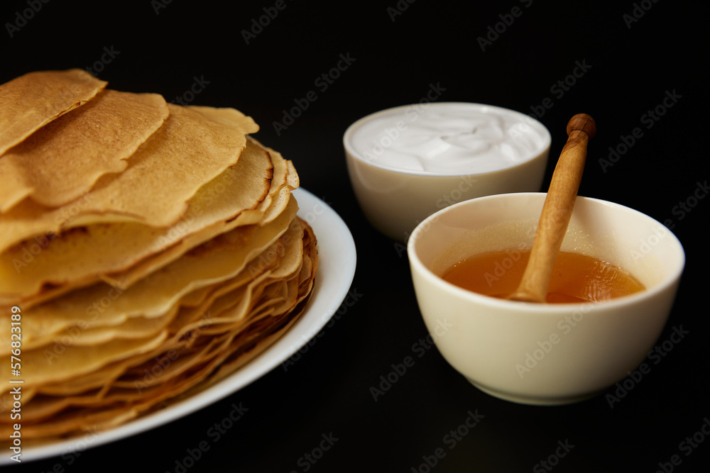 Thin pancakes with sour cream on board Thin pancakes with sour cream on board