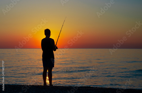 Ragazzo pescatore all alba, in riva al mare