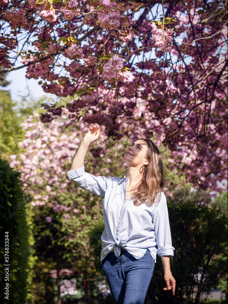 Beautiful smiling woman on the background of lilac pink cherry blossoms Beautiful smiling woman on the background of lilac pink cherry blossoms