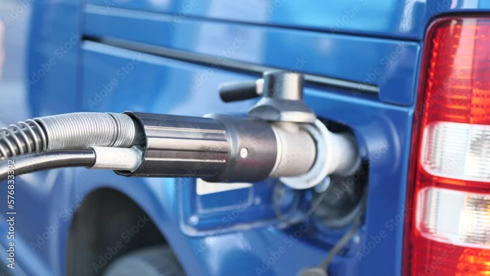 A man attaches a gas nozzle to a compressed natural gas CNG powered car