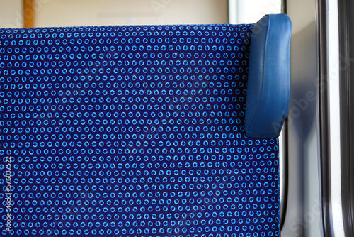 Close-up photo of a seat in a train. The seat is upholstered in blue fabric. We also see a headrest.