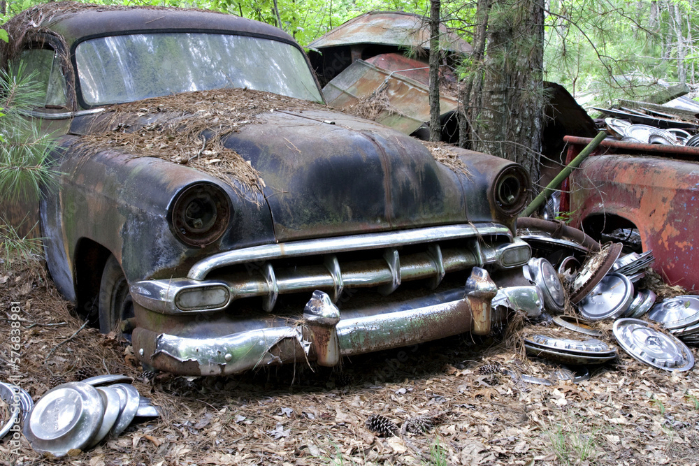 Old rusty American car in a scrap yard