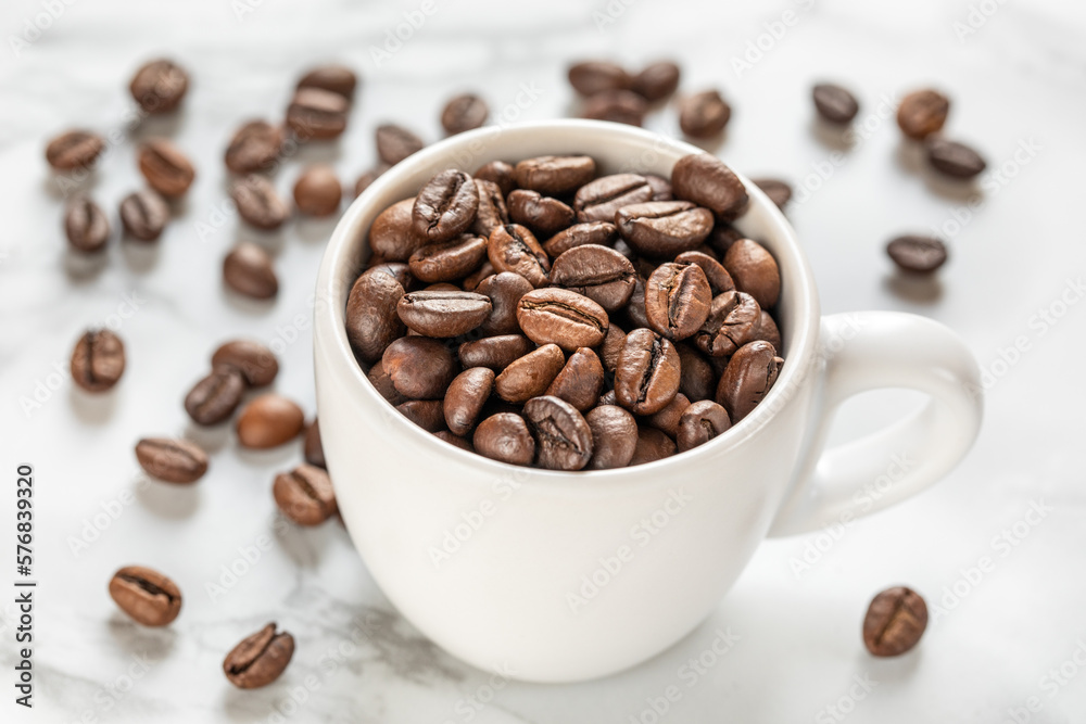 White cup with roasted coffee beans close up, white background. Good mood