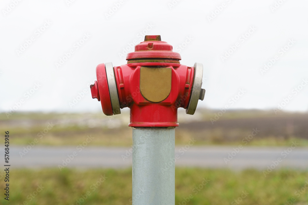 A bright red fire hydrant stands beside the road A bright red fire hydrant stands beside the road