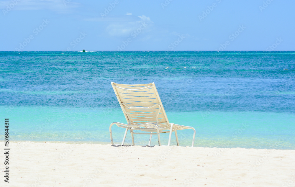 A white chair on the beach. Caribbean holiday vibes. Space for copy. 