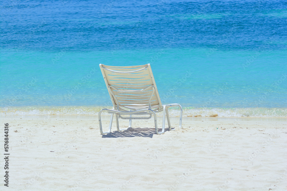 A white chair on the beach. Caribbean holiday vibes. Space for copy. 