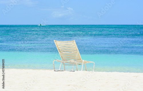 A white chair on the beach. Caribbean holiday vibes. Space for copy.  © Lara Red