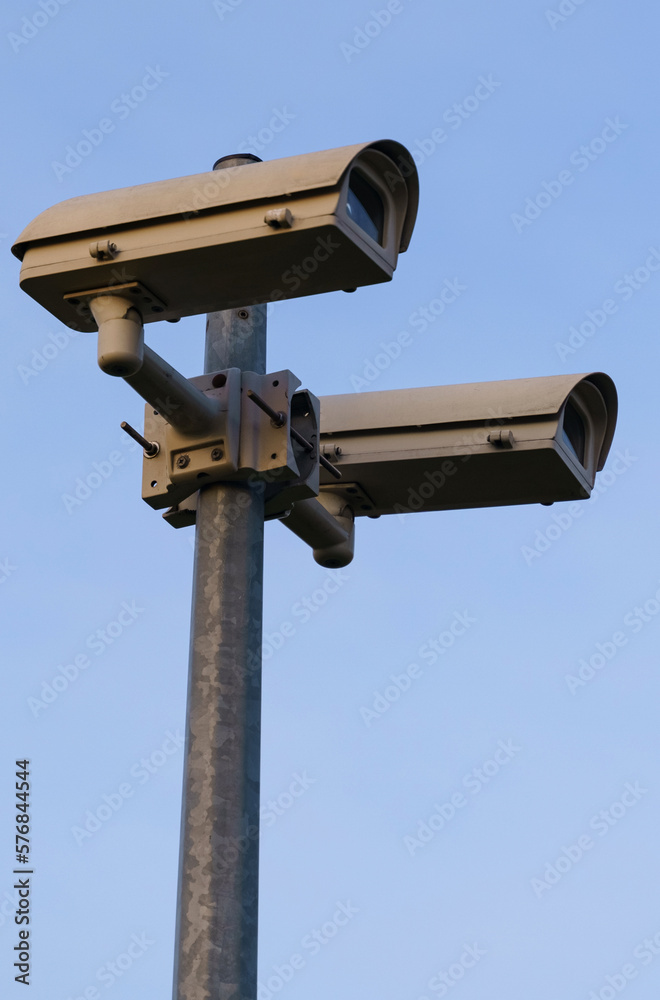 Surveillance cameras mounted on a pole against the blue sky. Surveillance cameras mounted on a pole against the blue sky.