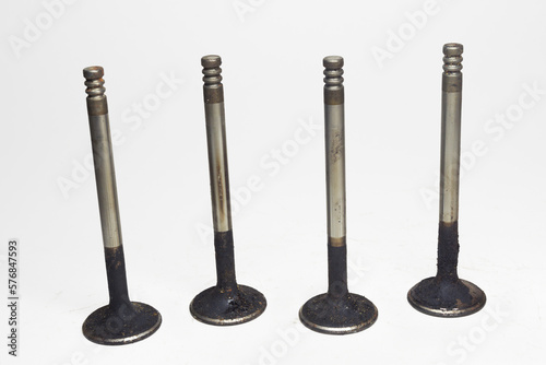 inlet poppet valves, previously used in car engine. black sludge deposits formations and burnt motor oil on steel alloy smooth surface of valve stem and head. on white background, with clipping path