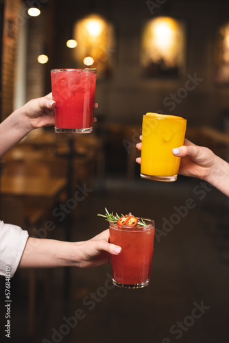 Cocktail party. Women's hands with colorful drinks on bokeh background. alcohol party