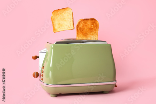 Toaster with crispy bread slices on pink background