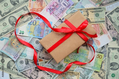 Money is laid out on the table, a box of different denominations of currency on top, a surprise gift with a red bow. Concept forex market, stock exchange, rise and fall. Flat lay.