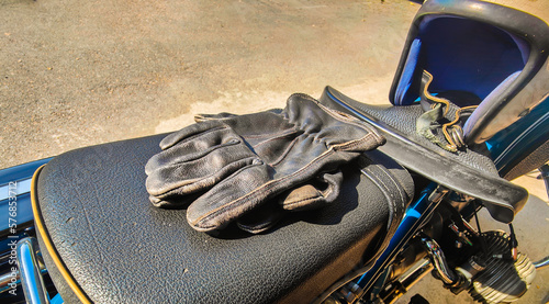 Old leather gloves lay on the motorcycle seat.