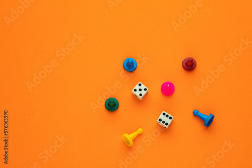 Colorful game chips and two dice are placed on an orange background
