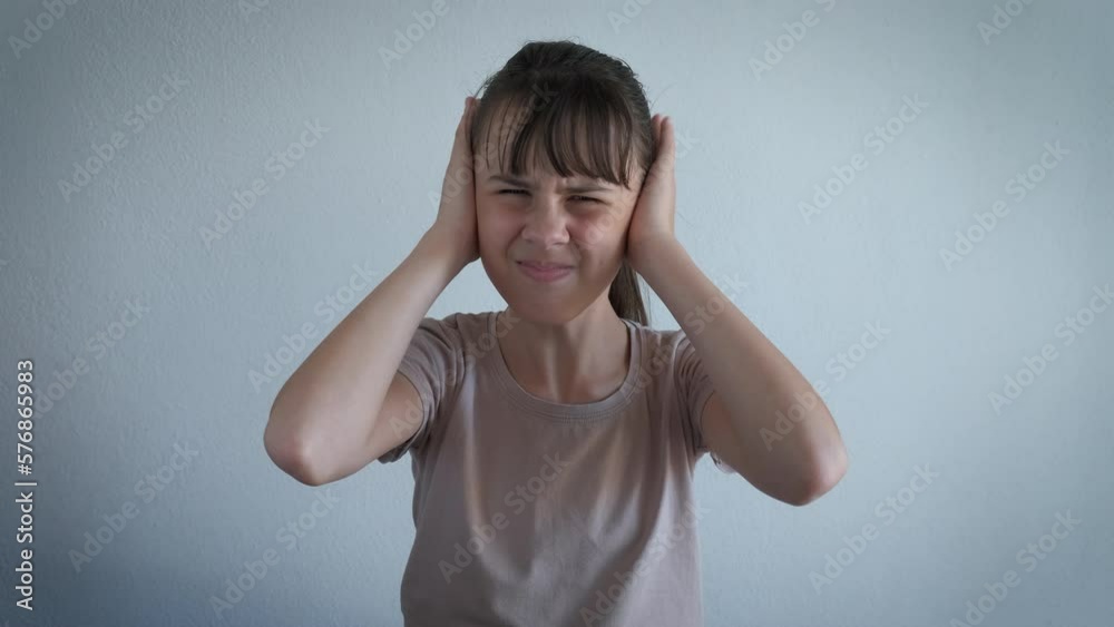 Feel stress from neighbor apartment. A teen try to relax in her flat and cover her ears with hands in the room.