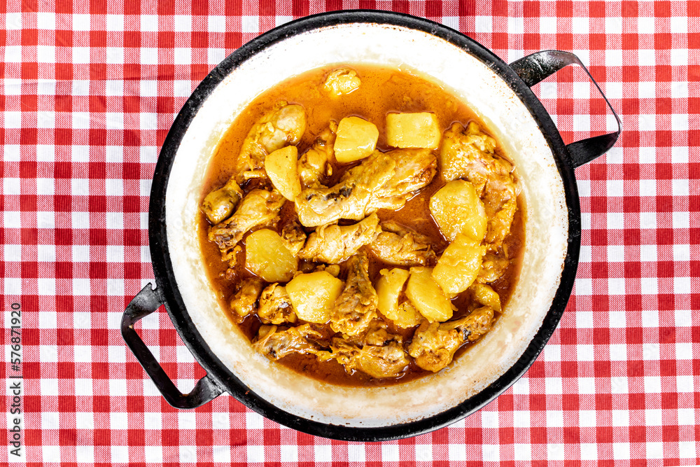 homemade chicken stew with tomato, onion and potato on checkered tablecloth