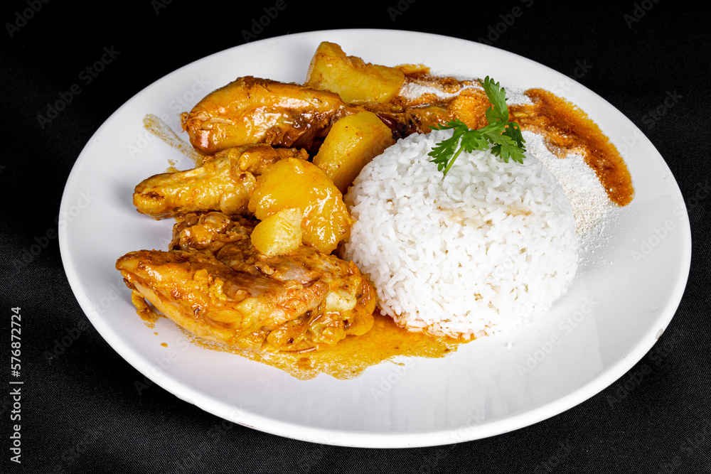 homemade chicken stew with tomato, onion and potato on black fabric table and plate with rice homemade chicken stew with tomato, onion and potato on black fabric table and plate with rice