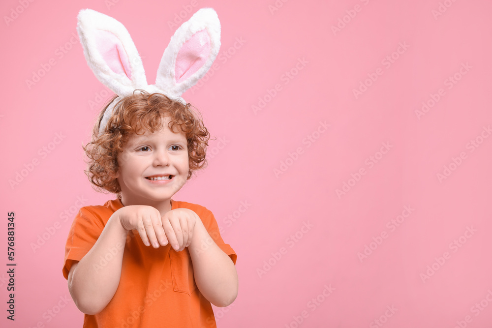 Happy boy wearing cute bunny ears headband on pink background, space for text. Easter celebration