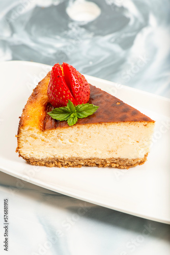 Creamy New York Cheesecake topped with fresh flowers, mint leaves, and strawberries.