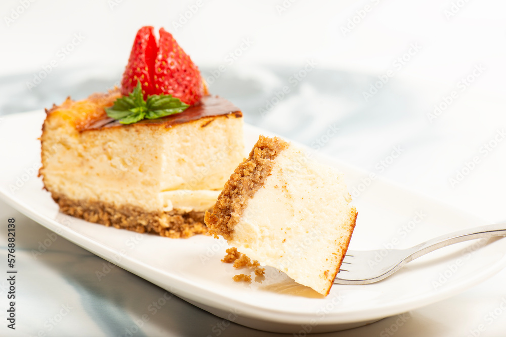 Creamy New York Cheesecake topped with fresh flowers, mint leaves, and strawberries.