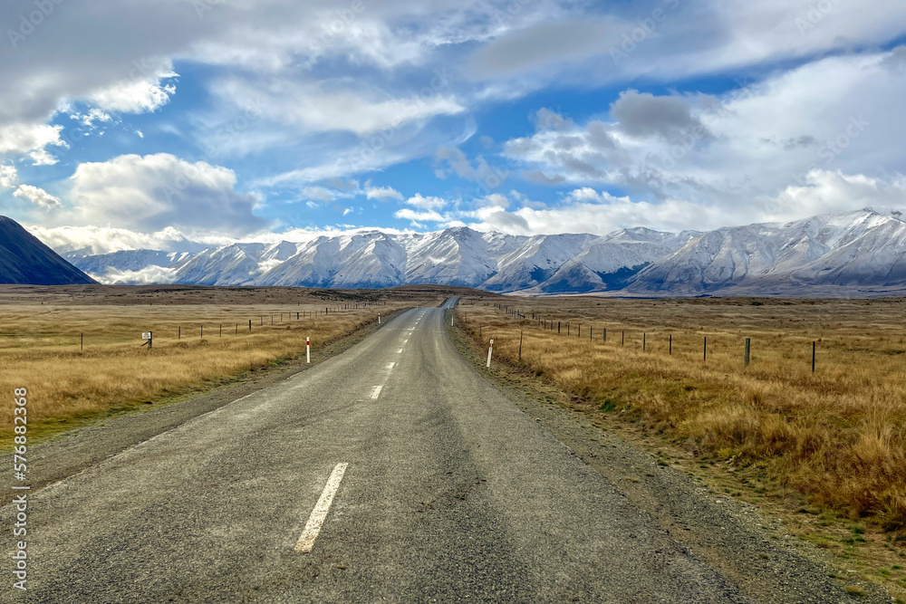 The long country road winding its way through the grass and tussock valley being grazed by farmers on the way to the Ben Ohau snow capped mountain range The long country road winding its way through the grass and tussock valley being grazed by farmers on the way to the Ben Ohau snow capped mountain range