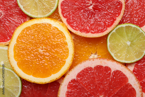 Slices of different citrus fruits as background  top view