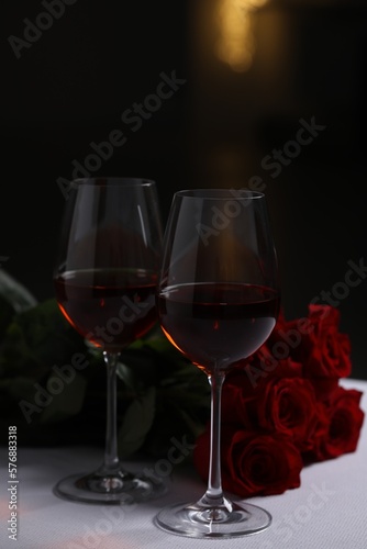 Glasses of red wine and rose flowers on white table. Romantic atmosphere