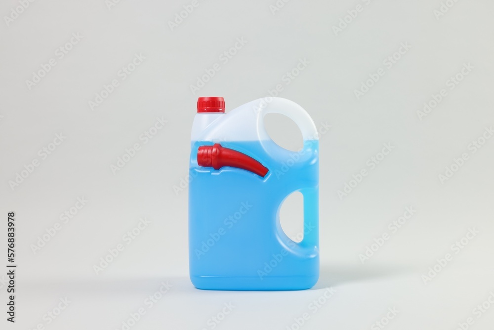 Plastic canister with nozzle and blue liquid on light grey background Plastic canister with nozzle and blue liquid on light grey background