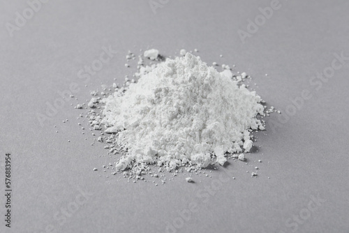 Heap of calcium carbonate powder on light grey table, closeup photo