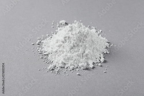 Heap of calcium carbonate powder on light grey table, closeup