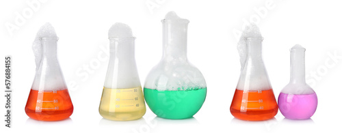 Set of laboratory flasks with colorful liquids and foam on white background. Chemical reaction