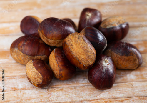 Unpeeled edible sweet chestnuts on wooden background, cooking ingredients