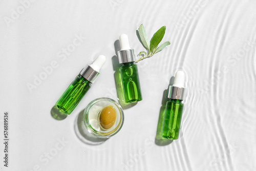 Bottles of essential olive oil in water on white background