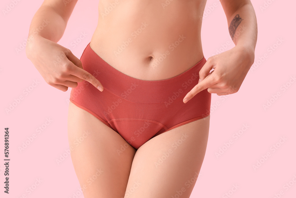Young woman pointing at menstrual panties on pink background, closeup - obrazy, fototapety, plakaty 