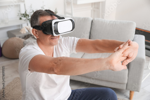 Mature man in VR glasses training at home