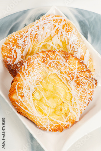 Fresh baked apple and custard danish topped with white fondant and icing sugar.
