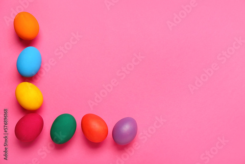 Frame made of colorful Easter eggs on pink background