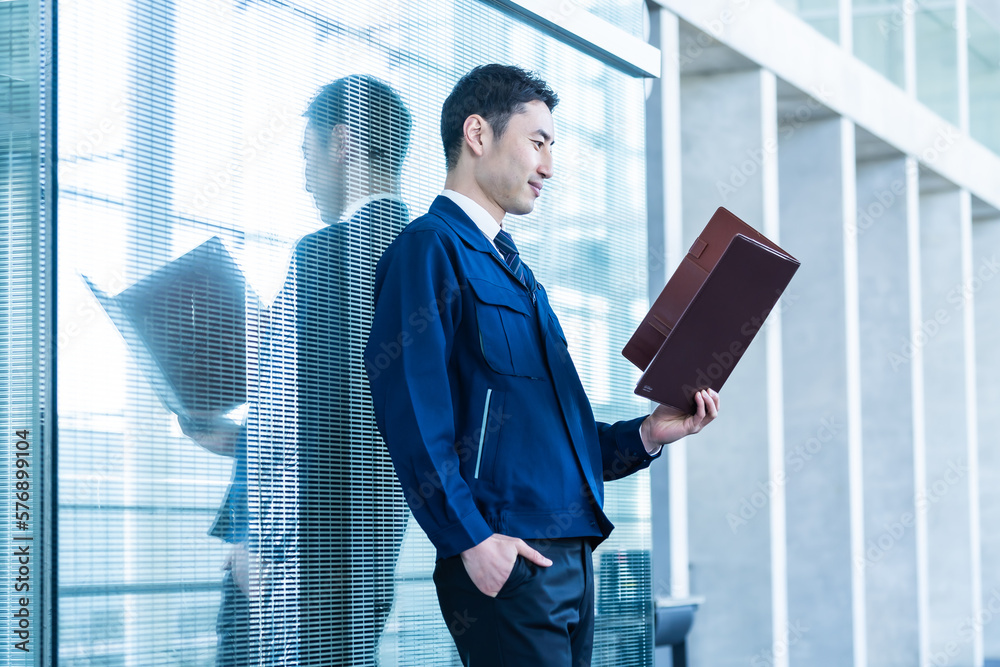 ファイルを持つ作業服を着た日本人