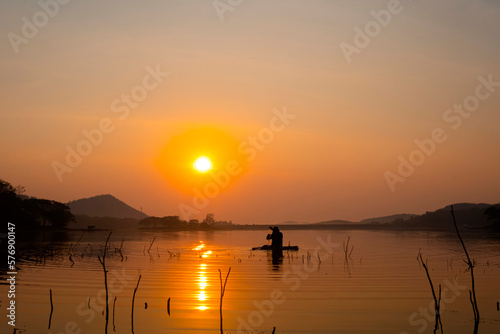 Fishermen is boats gently glide on the reservoir s calm waters during sunrise as they cast their nets and the stillness of the water creates a mirror like reflection