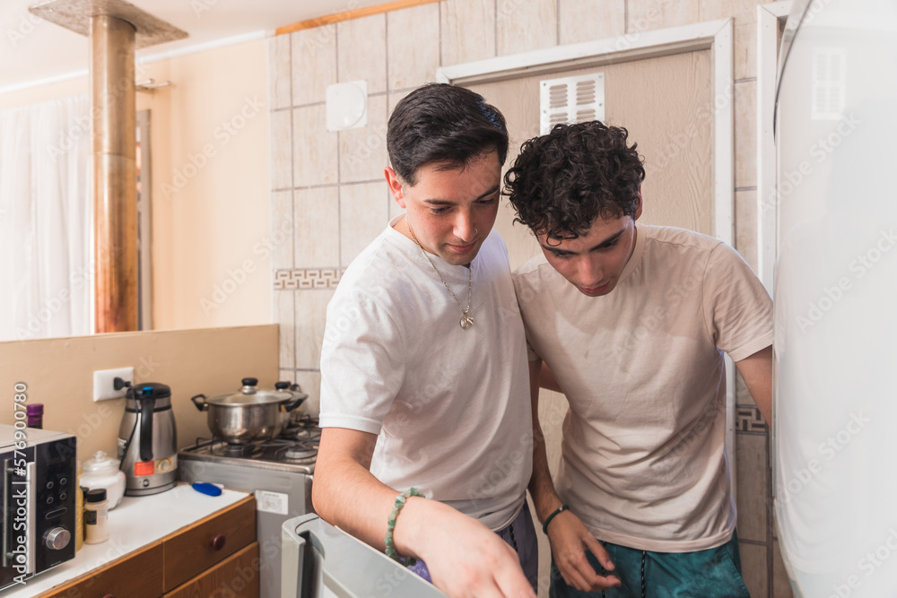 Young gay couple in pajamas looking inside the fridge to prepare breakfast in the morning. Young gay couple in pajamas looking inside the fridge to prepare breakfast in the morning.