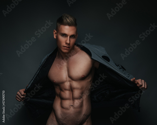 Fashion portrait of young sexy man with six pack abs wearing grey jacket on dark background фототапет
