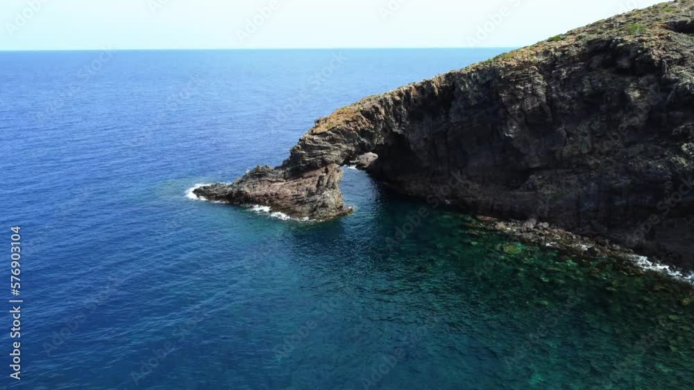 Drone shot through the Elephant Arch, rock formation in Pantelleria, Sicily, Italy Drone shot through the Elephant Arch, rock formation in Pantelleria, Sicily, Italy