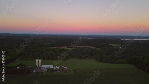 Aerial dolly forward shot of a farm tucked into the hills near Traverse City Michigan during sunset with a beautiful gradient of color in the sky photo