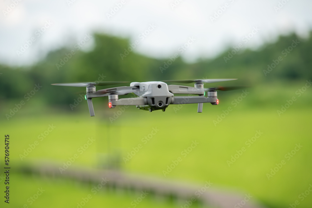 A flying drone in the open air, Drone in the rice field with green rice fields in the background, Technology innovation in agricultural industry.