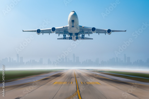 Airplane business or cargo transportation taking off from runway airport to destination with building city scape background.