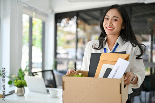 фотографія Excited Asian female office worker feels happy to quit her job, holding a cardbo