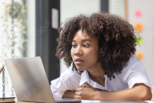Portrait of tired young business african american woman work with documents tax laptop computer in office. Sad, unhappy, Worried, Depression, or employee life stress concept 